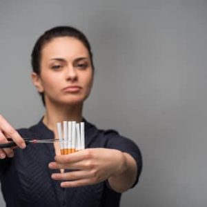 Woman cutting up cigarettes to quit smoking using hypnotherapy